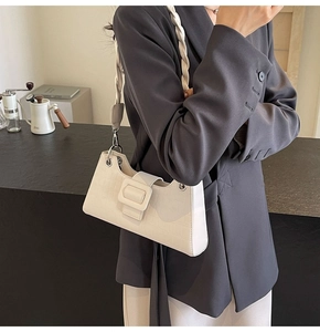 Detailed texture of white crocodile pattern leather baguette bag with woven shoulder strap