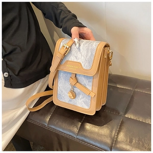 Detail of light blue marble pattern mini crossbody bag with brown leather trim and gold charm