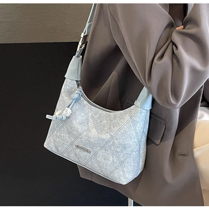 Detailed view of light blue denim texture shoulder bag with quilted stitching and logo