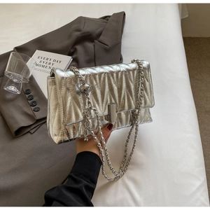 Détail du sac argenté matelassé avec texture en V et chaîne à perles métalliques ciselées