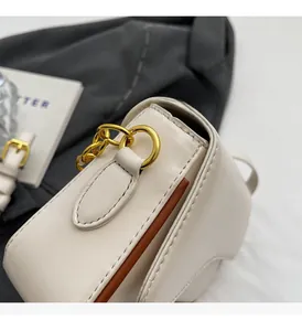 Details der goldenen Beschläge und braunen Kanten an der beigen Lederhandtasche