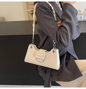 Detail of white crocodile texture baguette bag with woven shoulder strap and buckle