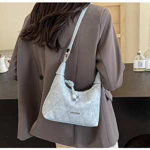 Detail of light blue hobo bag with quilted stitching and decorative knot on shoulder strap