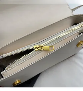 Detailansicht goldener Metallreißverschluss und Fischgrät-Innenfutter der elfenbeinfarben Tasche
