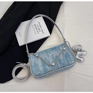 Close-up of light blue denim shoulder bag with silver chain and cute elephant charm
