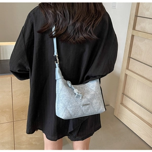 Detail of light blue denim crossbody bag with diamond stitching and metal logo