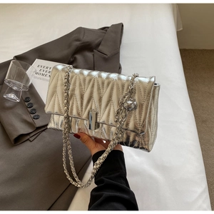 Détail du sac matelassé argenté avec finition métallique et charm boule chic