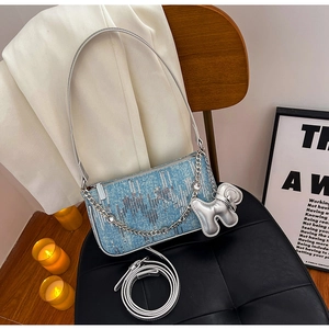 Close-up of light blue sequined denim shoulder bag with silver chain and dog charm