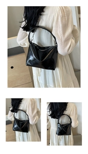 Detail of black glossy handbag with silver chain strap and smooth metal zipper