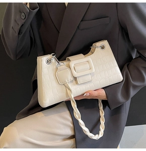 Detail of cream white faux crocodile leather underarm bag with braided handle