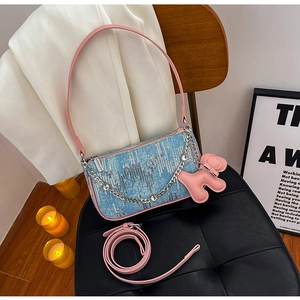 Detail of blue denim sequin bag with rhinestone chain and pink puppy charm accessory