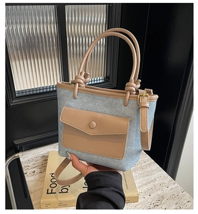 Détail du sac seau en denim bleu clair avec garniture en cuir brun et poignée nouée