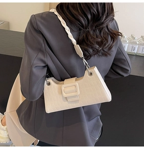 Detail of creamy white faux crocodile skin bag with braided strap and silver buckle