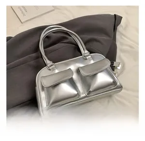 Detail of silver metallic handbag featuring two front flap pockets and cylindrical handles