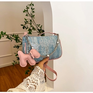 Detail of blue sequin shoulder bag with pink leather trim and a cute puppy charm