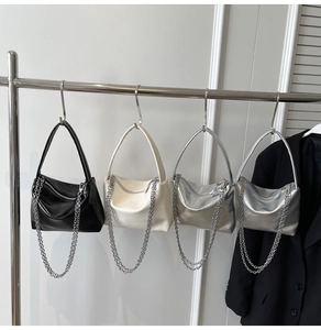 Detail showing minimalist underarm bags in black, white and silver with hanging metal chains