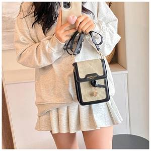Detail of a chic contrast shoulder bag with golden hardware and tassel, shown on model