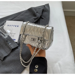 Détail du sac bandoulière argenté matelassé avec chaîne et sphère métallique