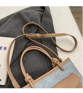 Détail du sac seau en denim montrant la poignée nouée et la bandoulière en cuir