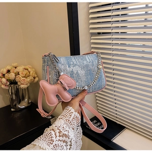 Detail of blue sequin denim bag with pink leather strap and butterfly charm accessory