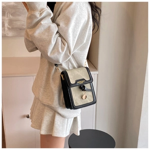 Detail of green crossbody square bag with gold lettering and black leather knot strap