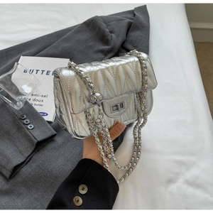 Détail du sac matelassé argenté avec bandoulière chaîne et fermoir pivotant