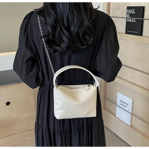 Detailed macro view of white glossy leather handbag with elegant silver chain strap