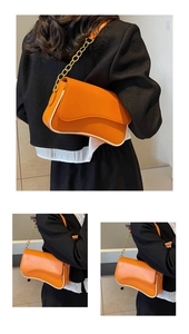 Detail der orangefarbenen Umhängetasche mit gewelltem Boden und goldener Kette