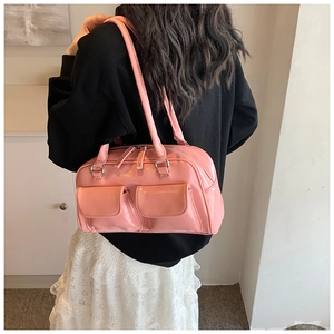 Detail of pink patent leather shoulder bag with glossy finish and front flap pockets