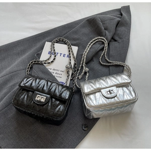 Détail de mini sacs matelassés noir et argent sur blazer gris avec fermoirs métalliques
