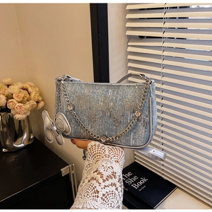 Detail of light blue denim shoulder bag with silver sequins and a bow charm