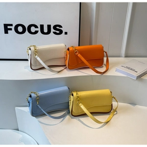 Detailansicht von vier schicken Unterarmtaschen in Beige, Orange, Blau und Gelb mit Ketten