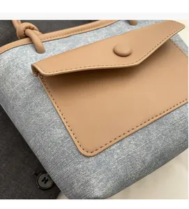 Détail du sac seau en denim bleu avec poche à rabat en cuir brun et coutures précises
