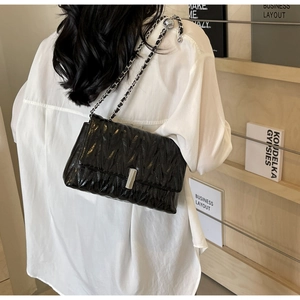 Détail du sac en cuir matelassé noir avec boucle argentée et bandoulière en chaîne