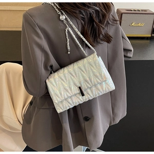 Détail du sac matelassé argent holographique avec bandoulière chaîne porté par le modèle