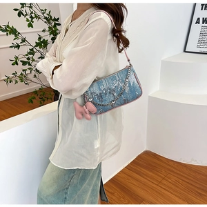 Detailed close-up of blue sequin denim shoulder bag with pink strap and animal charm