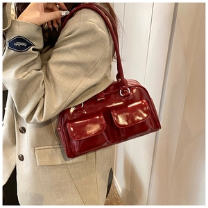 Detailed view of glossy burgundy underarm bag with front pockets and patent finish