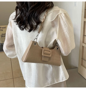 Detail of beige faux crocodile texture shoulder bag with woven strap and square buckle