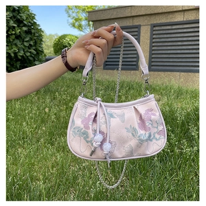 Detail of floral embroidery on pink chain handbag with vintage curved top handle