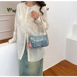 Detail view of denim blue sequined bag with pink leather strap and butterfly charm accessory