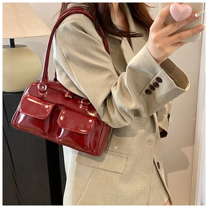Deep red patent leather underarm bag worn by model in a stylish lifestyle setting