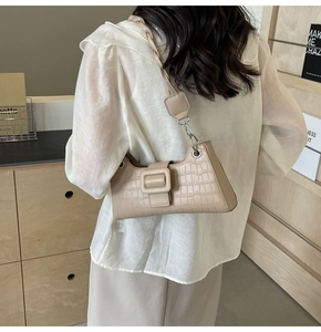 Detail of beige crocodile pattern baguette bag with twisted strap and silver hardware