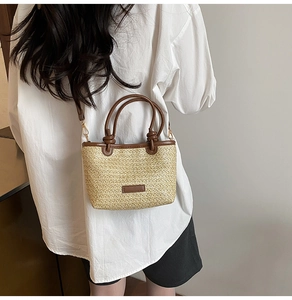 Détails d'un sac seau en paille tressée avec finitions en cuir marron et boucles dorées