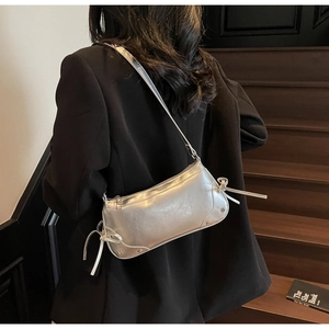 Dettaglio borsa a spalla argento metallizzato con fiocchi e rivetti alla moda