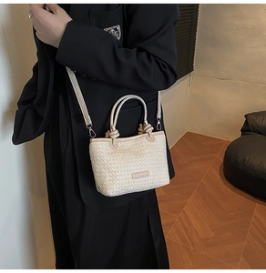 Détail d'un sac seau en paille avec texture tissée crème et bandoulière en cuir