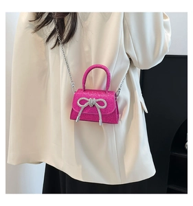 Detail of rose pink glitter mini bag with silver bow accent and metallic chain strap