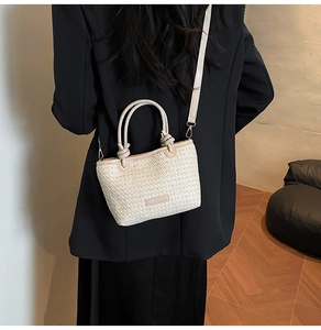 Détail d'un sac seau en paille tressée avec textures contrastées et bandoulière amovible
