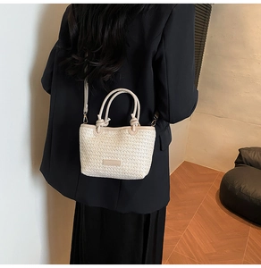 Détail d'un sac cabas en paille tissée avec bandoulière porté par un mannequin en style