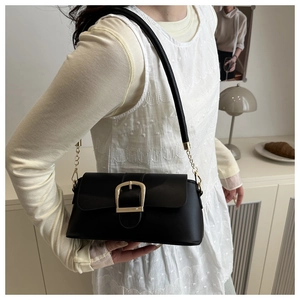 Detail of a minimalist black underarm bag with a vintage gold horseshoe buckle feature