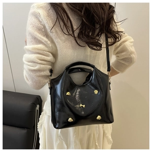 Detail of black glossy handbag with gold dog motifs shown on person from behind